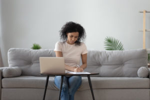 Black woman sitting at coffee table holding pen writing