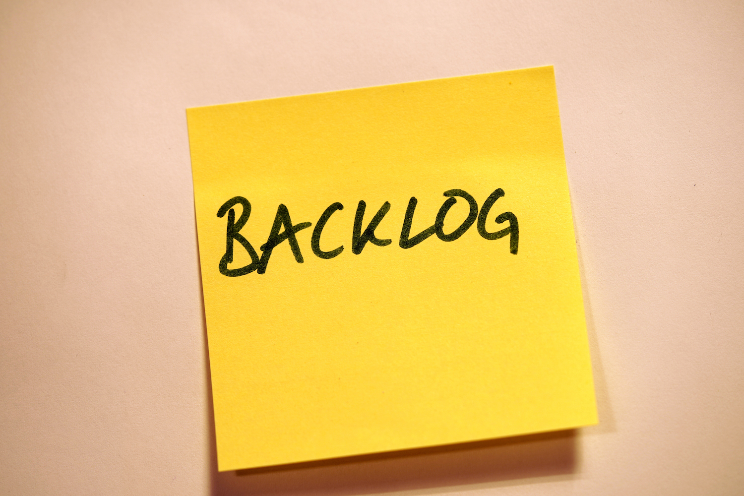 Yellow sticky note with "backlog" written on it in black marker
