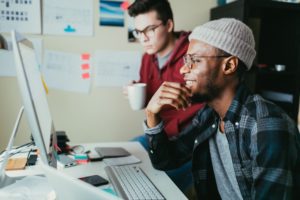 Two men work at a computer solving QA issues