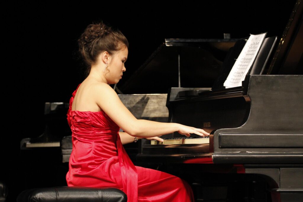 Abby Edwards, Surge senior business analyst, sitting at a piano playing a recital