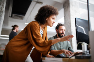 One Black woman and one white man look at a computer screen